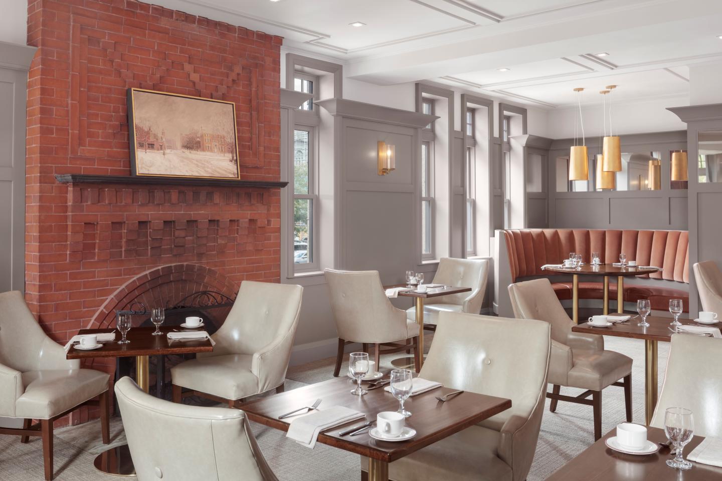 Cozy restaurant with beige chairs, red booths, and a brick fireplace.