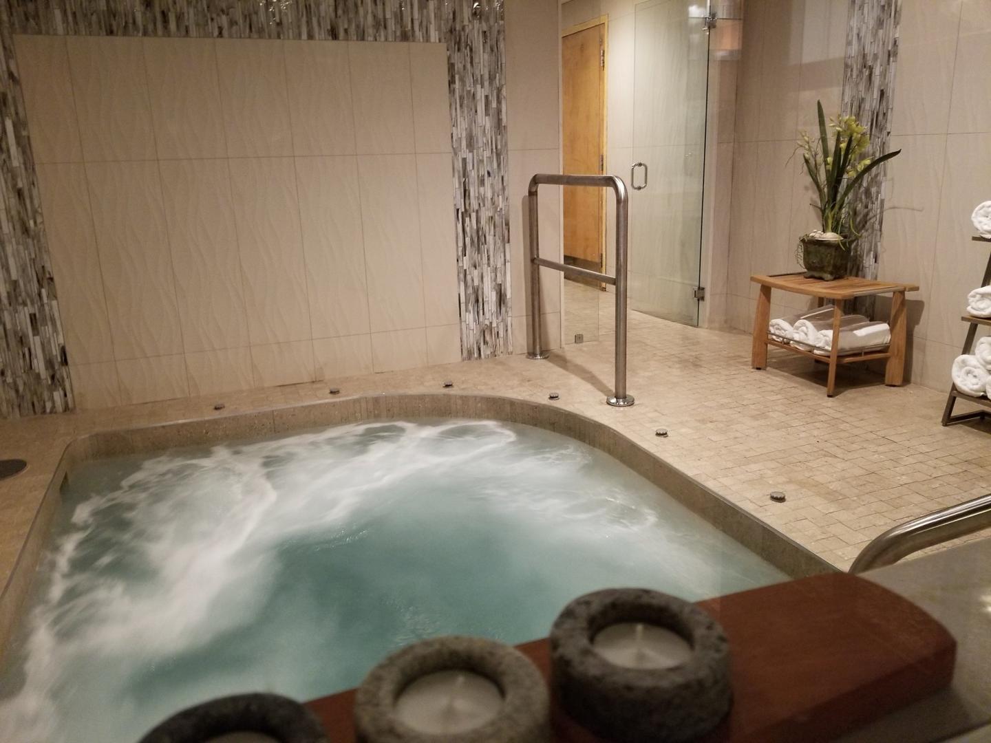 Jaccuzi spa in a serene room with candles and towels.