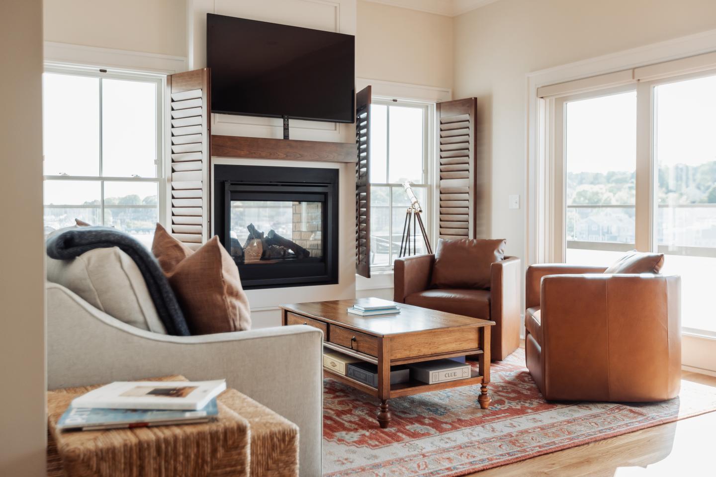 Cozy living room with fireplace, leather chairs, and a large window.