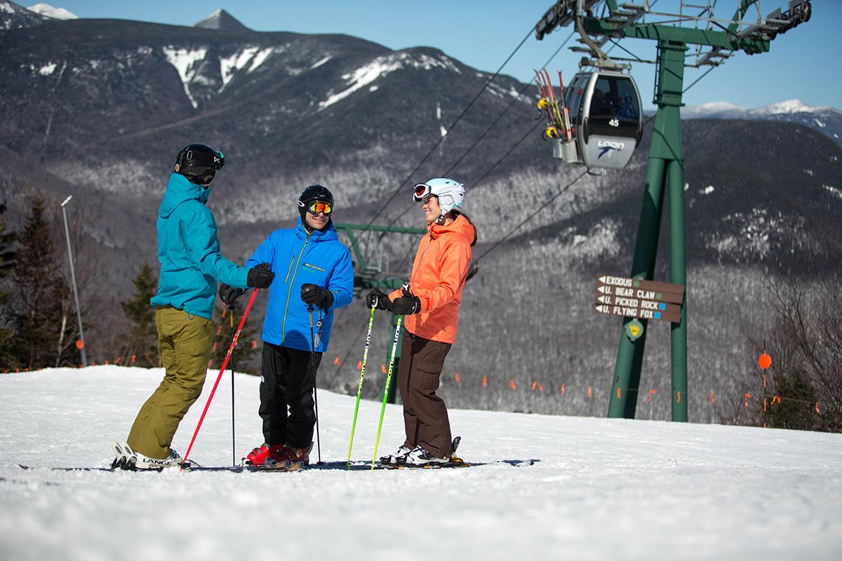 Three skiers standing under a chairlift 