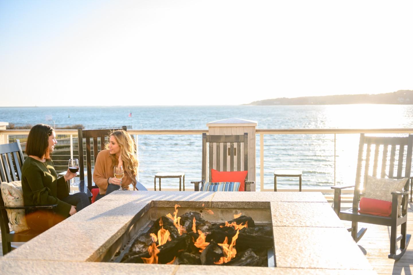 Two people enjoying drinks on a deck with an ocean view